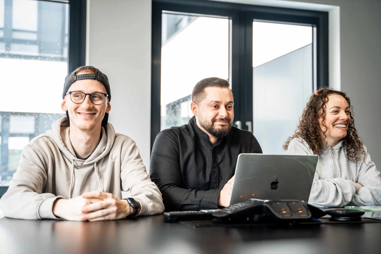 Drei Mitarbeitende von SUMAX am Besprechungstisch mit Laptop
