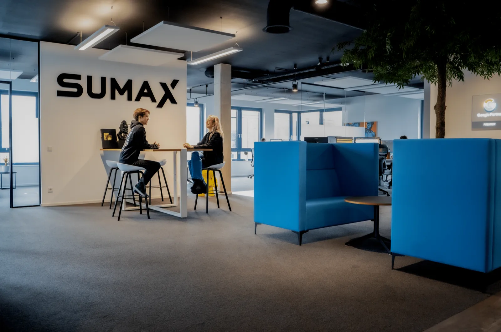 Zwei Mitarbeitende im Gespräch an einem Stehtisch im SUMAX-Büro